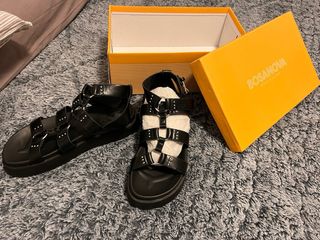 Sandalias negras con tiras y hebillas plateadas.