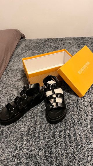 Sandalias negras con tiras y hebillas plateadas.
