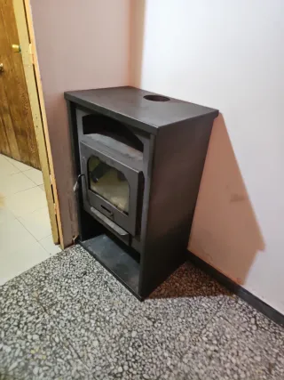 Estufa de leña metálica con puerta de cristal