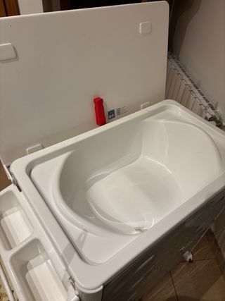 Cambiador con bañera y cajonera gris y blanco.