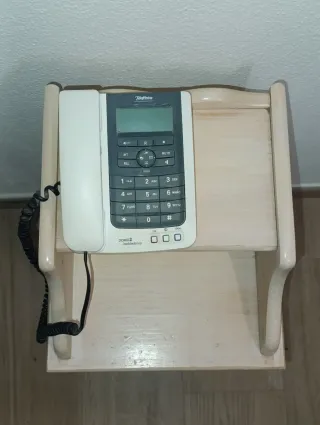 Telefonera beige con teléfono fijo