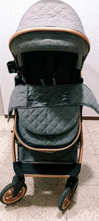 Carrito de bebé gris con detalles dorados