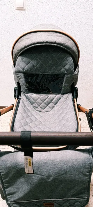 Carrito de bebé gris con detalles dorados