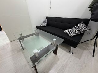 Sofá cama negro y mesa de cristal