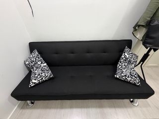 Sofá cama negro y mesa de cristal