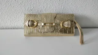 Bolso de fiesta dorado con asa de mano.