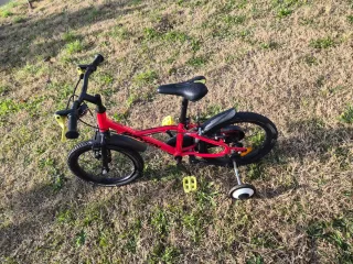 Bicicleta BTWIN infantil roja con ruedines.