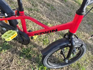 Bicicleta BTWIN infantil roja con ruedines.