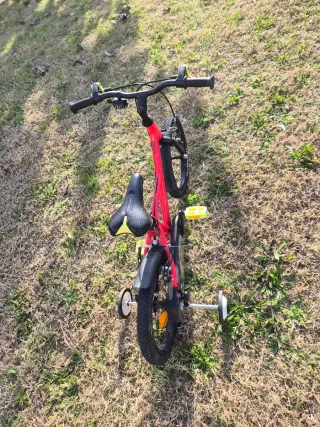 Bicicleta BTWIN infantil roja con ruedines.