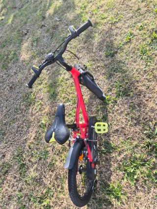 Bicicleta BTWIN infantil roja con ruedines.