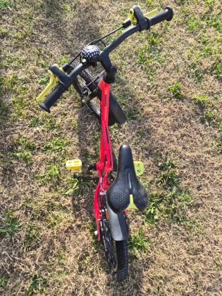 Bicicleta BTWIN infantil roja con ruedines.