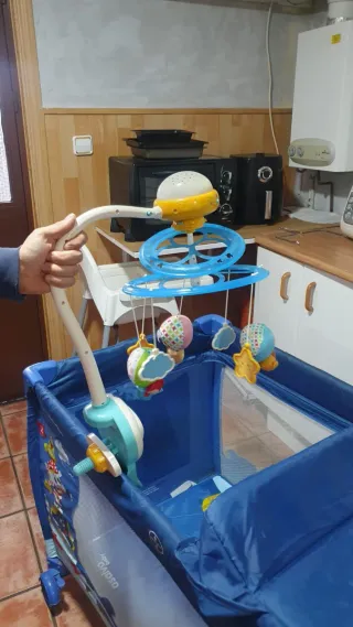 Cuna de viaje azul con estampado infantil.