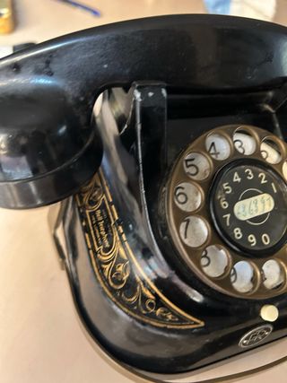 Teléfono antiguo negro y dorado funcionando