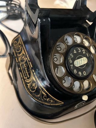 Teléfono antiguo negro y dorado funcionando