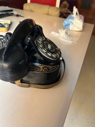 Teléfono antiguo negro y dorado funcionando