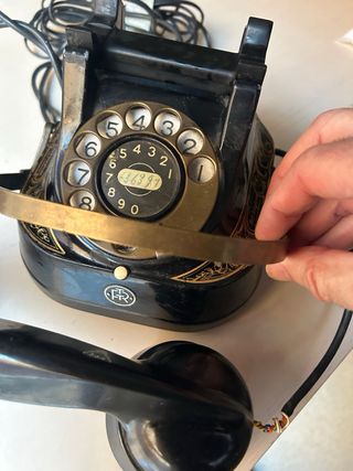 Teléfono antiguo negro y dorado funcionando