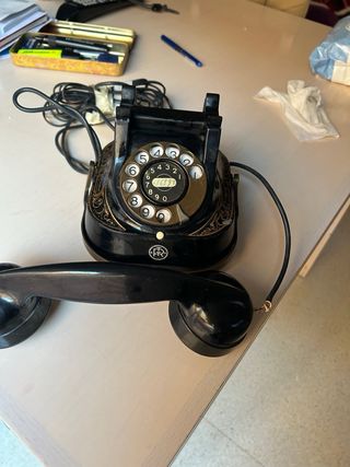 Teléfono antiguo negro y dorado funcionando