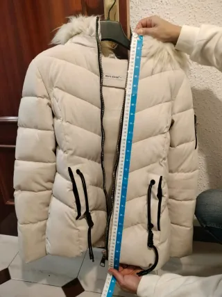 Abrigo acolchado blanco crudo con capucha de pelo.