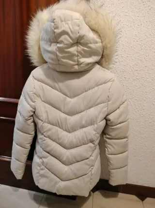 Abrigo acolchado blanco crudo con capucha de pelo.