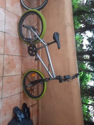 Bicicleta BMX plateada con ruedas verdes