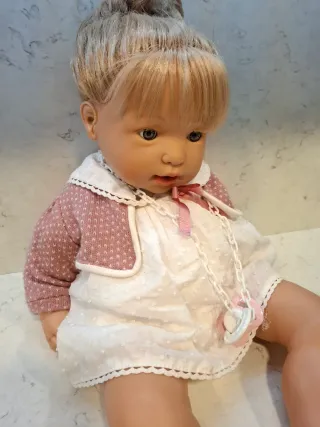 Muñeca bebé con vestido blanco y rebeca rosa