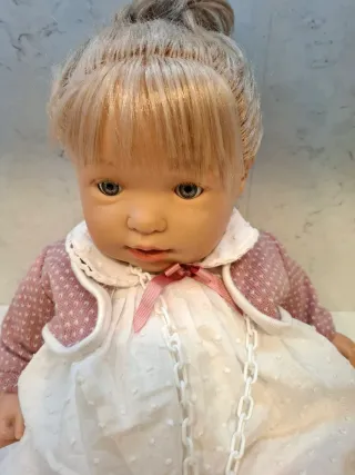 Muñeca bebé con vestido blanco y rebeca rosa