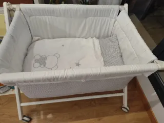 MiniCuna de bebé de madera blanca con ruedas.