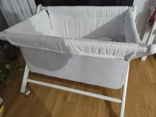 MiniCuna de bebé de madera blanca con ruedas.