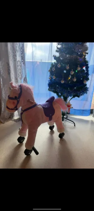 Caballo rosa con ruedas y montura morada.
