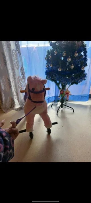 Caballo rosa con ruedas y montura morada.