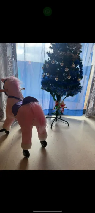 Caballo rosa con ruedas y montura morada.