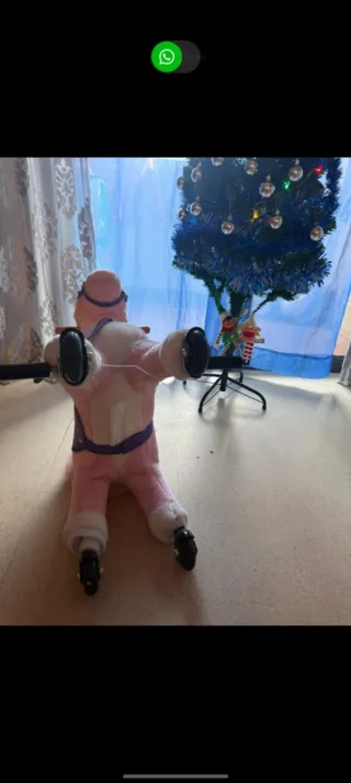 Caballo rosa con ruedas y montura morada.