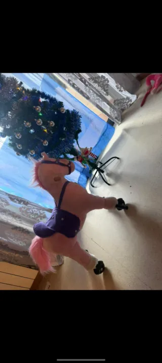 Caballo rosa con ruedas y montura morada.