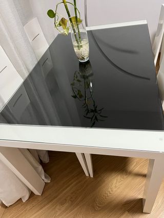 Mesa comedor cristal negro y 4 sillas blancas.