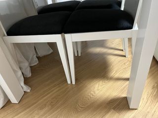Mesa comedor cristal negro y 4 sillas blancas.