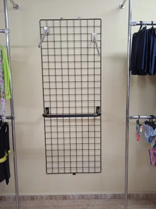 Varios percheros de malla y tubo con estantes