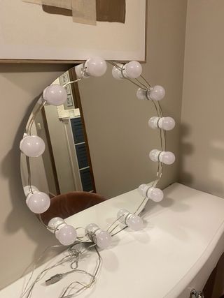 Tocador blanco con espejo con luces y silla rosa