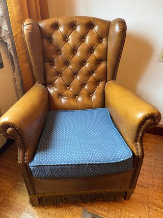 Sillón de piel marrón con cojín azul