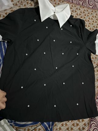 Camisa negra con cuello blanco y perlas
