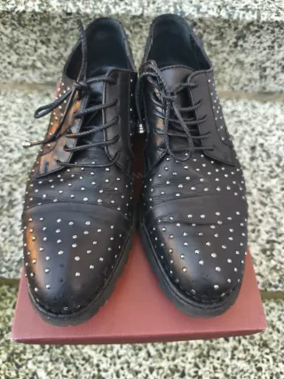 Scarpe nere con borchiette luccicose.