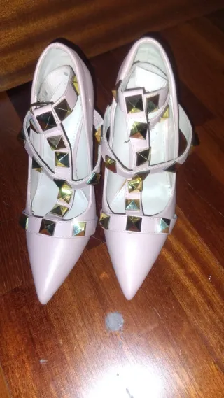 Zapatos de tacón rosa con tachuelas doradas