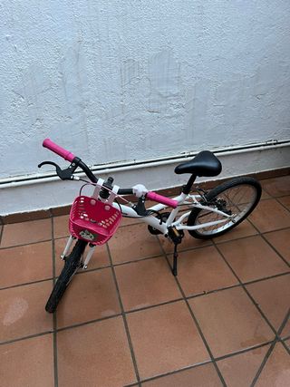 Bicicleta infantil blanca y rosa, con caballete.