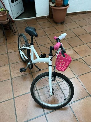 Bicicleta infantil blanca y rosa, con caballete.