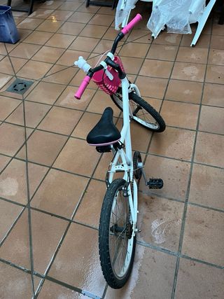 Bicicleta infantil blanca y rosa, con caballete.