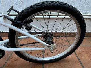 Bicicleta infantil blanca y rosa, con caballete.