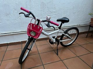 Bicicleta infantil blanca y rosa, con caballete.