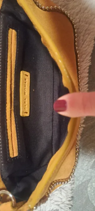 Bolso de ante de color mostaza con cadena.