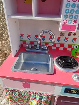 Cocinita de madera con muñecas y bolsa de frutas