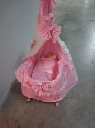 Cuna de bebé rosa con muñeca