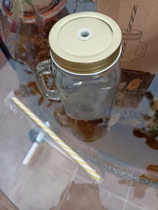 Vaso de cristal con tapa dorada y pajita